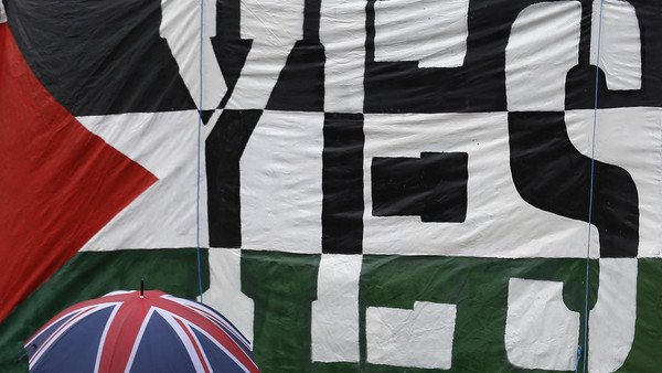 A passer-by carries a Union Flag umbrella past a pro-Palestine demonstration outside the Houses of Parliament in London October 13, 2014. (Reuters) 