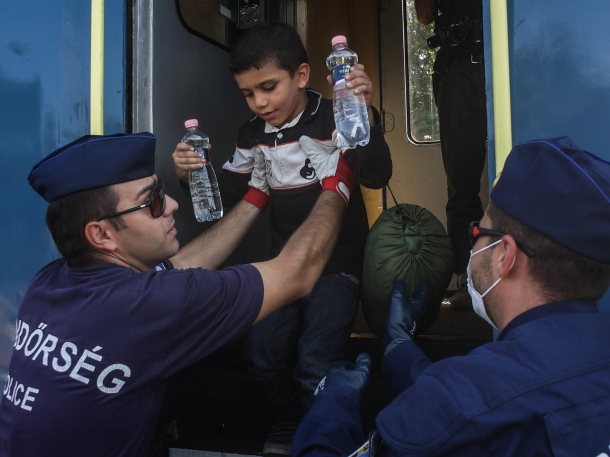 Hungarian police officers help a Syrian child at the railway station in Roszke, Hungary, on Monday. Thomas Campean / Anadolu Agency / Getty Images
