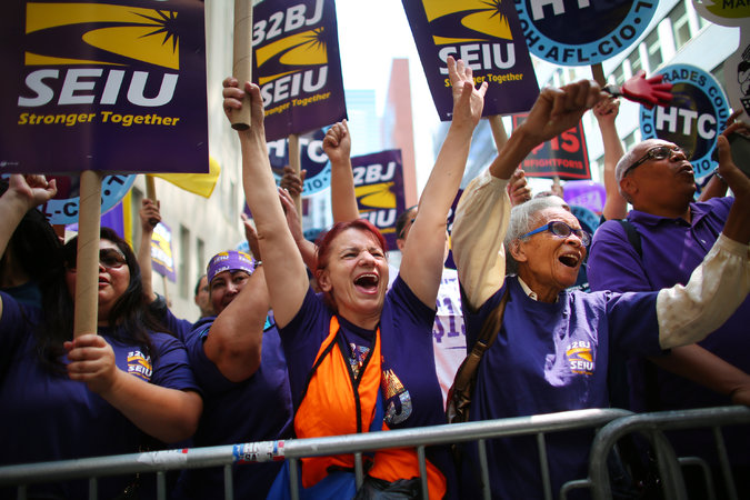  Fast-food workers and supporters gathered on Wednesday in Manhattan to watch a live video of the wage board’s decision. The governor hailed it as an example of New York’s progressiveness. Credit Chang W. Lee/The New York Times 
