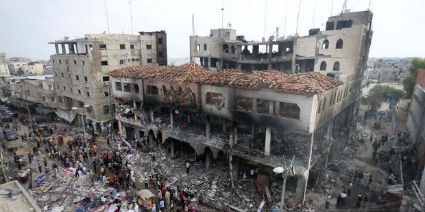 Palestinians gather around the remains of a commercial center, which witnesses said was hit by an Israeli air strike, in Rafah, 2014. © REUTERS/Ibraheem Abu Mustafa