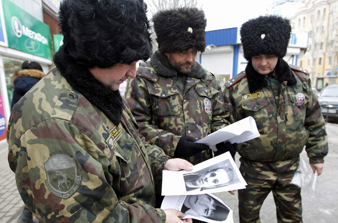 Russian security officers look at portraits of people suspected of involvement in terrorist acts [Reuters] 