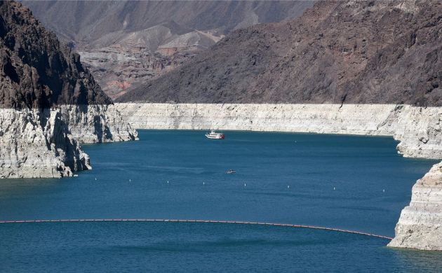 A paddle wheeler and a small motorboat sail on Lake Mead, North America's largest man-made reservoir. The water is at its lowest level since the Hoover Dam was built in the 1930s. The white "bathtub ring" of mineral deposits on the rocks marks past water levels. 