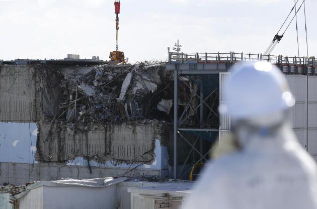  A member of the media, wearing a protective suit and a mask, looks at the No. 3 reactor building at Tokyo Electric Power Co's (TEPCO) tsunami-crippled Fukushima Daiichi nuclear power plant in Okuma town, Fukushima prefecture, Japan. Toru Hanai/Files/Reuters 
